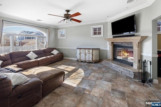 living area with visible vents, baseboards, a glass covered fireplace, and crown molding