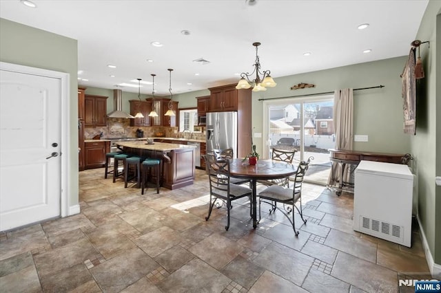 dining area with stone tile floors, recessed lighting, baseboards, and a chandelier