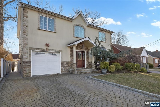 view of front of property featuring a gate, fence, stucco siding, a garage, and decorative driveway