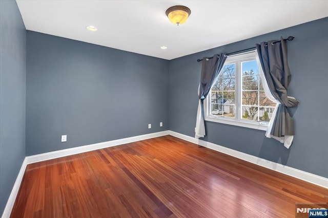 spare room featuring recessed lighting, baseboards, and wood finished floors