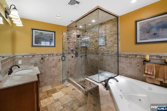 bathroom with visible vents, a whirlpool tub, tile walls, a shower stall, and vanity