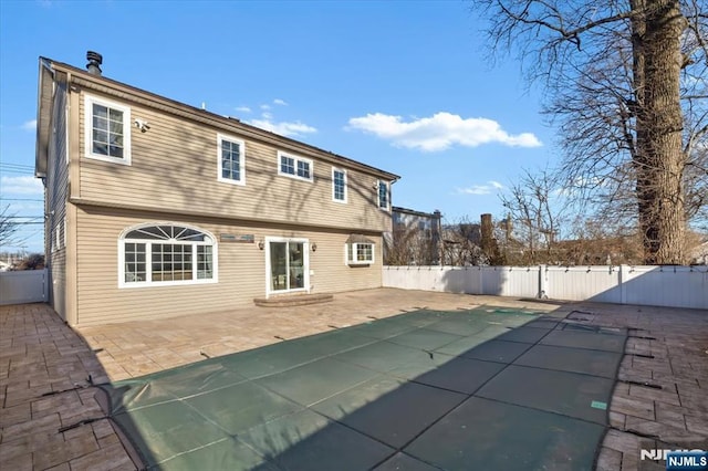 rear view of house featuring a patio, a fenced backyard, and a gate