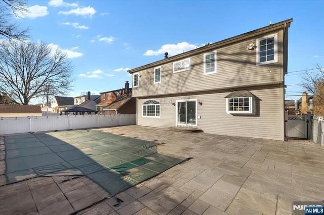 rear view of property with a patio, a fenced backyard, and a gate