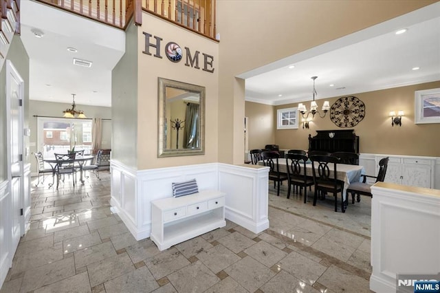 hallway with visible vents, crown molding, a chandelier, stone tile floors, and recessed lighting