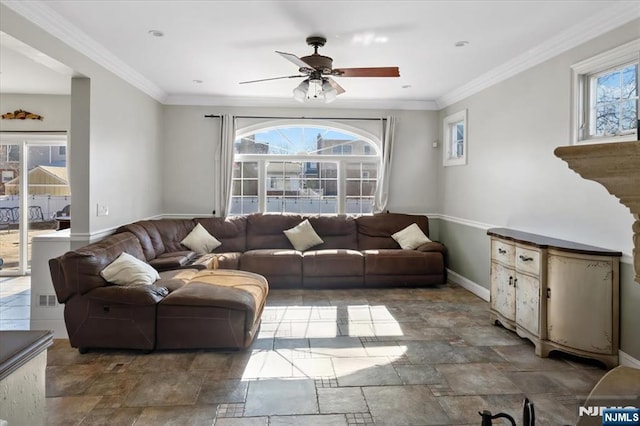 living room featuring stone finish flooring, baseboards, ornamental molding, and a ceiling fan