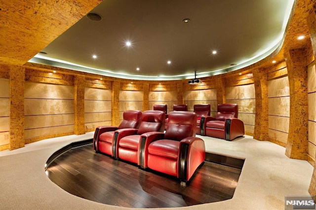 cinema room featuring wooden walls, a tray ceiling, and hardwood / wood-style flooring