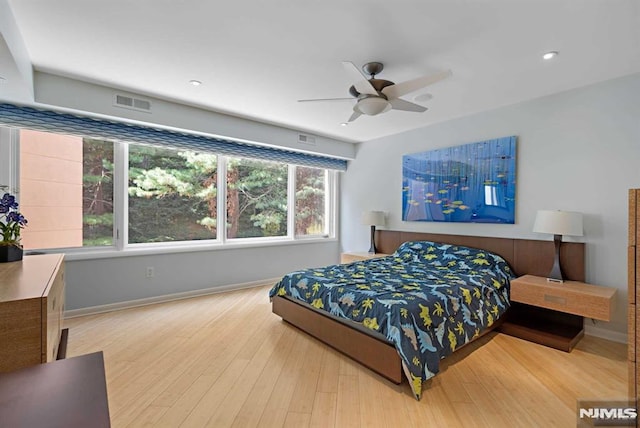 bedroom with ceiling fan, hardwood / wood-style flooring, and multiple windows