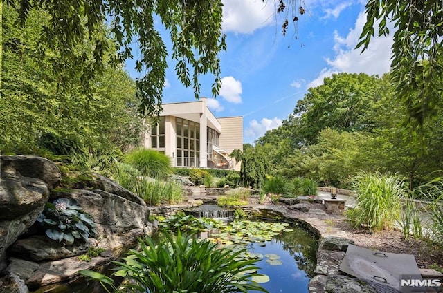 view of yard featuring a sunroom and a small pond