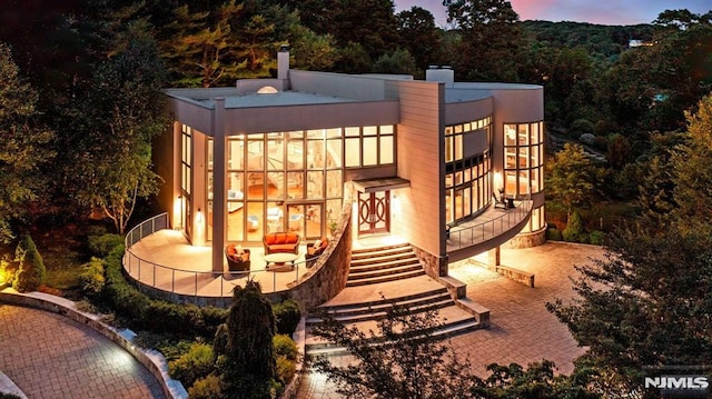 back house at dusk featuring a patio