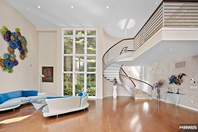 interior space featuring a wall of windows, a towering ceiling, and wood-type flooring