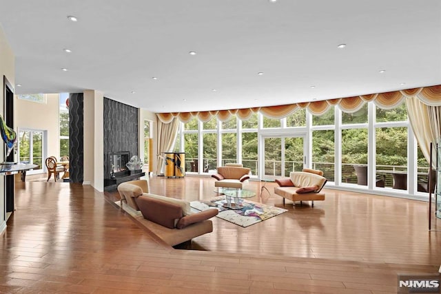 living room with hardwood / wood-style floors, a wall of windows, and a high end fireplace