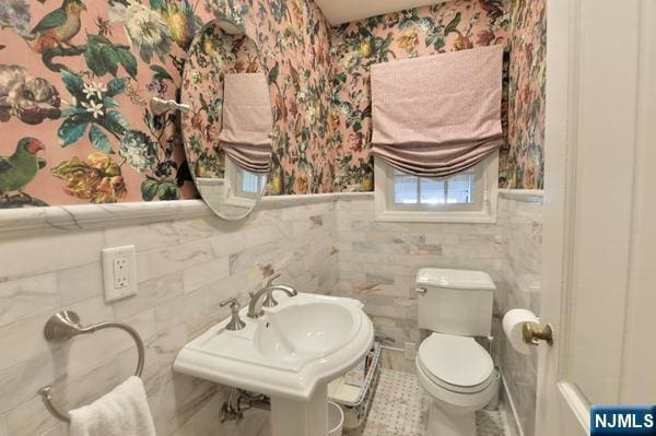 bathroom featuring tile walls, sink, and toilet