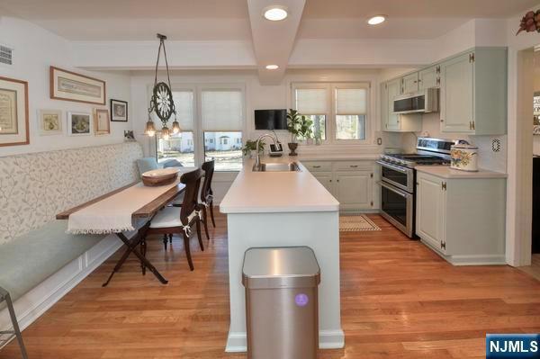 kitchen with decorative light fixtures, sink, range with two ovens, and light wood-type flooring