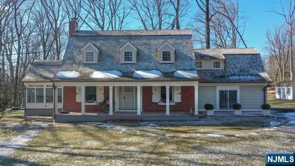 new england style home featuring a porch and a front yard