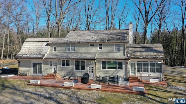 back of property with central AC unit and a patio