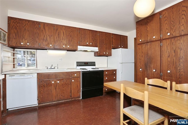 kitchen with white appliances, dark floors, light countertops, under cabinet range hood, and a sink