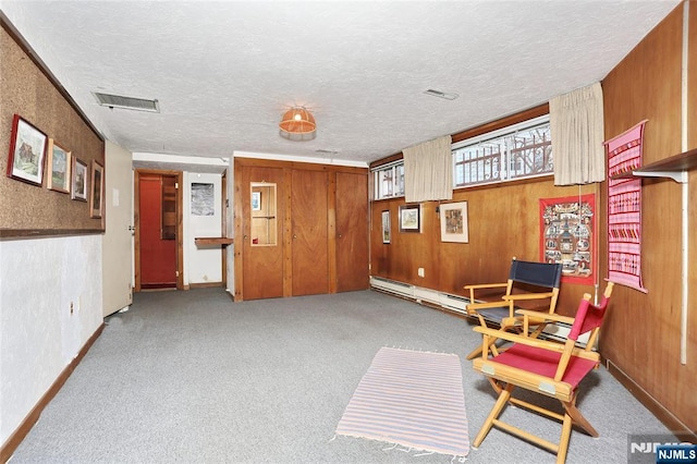 living area with a textured ceiling, light carpet, visible vents, and wooden walls