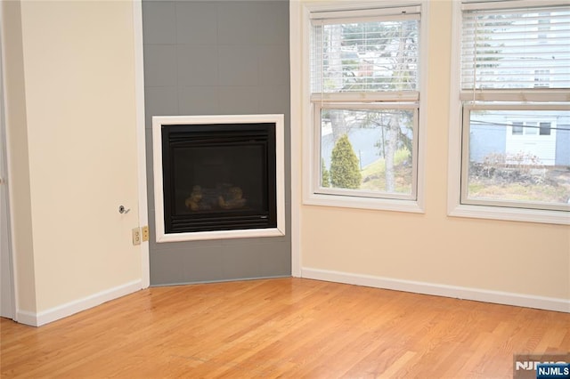 unfurnished living room with a large fireplace and light wood-type flooring