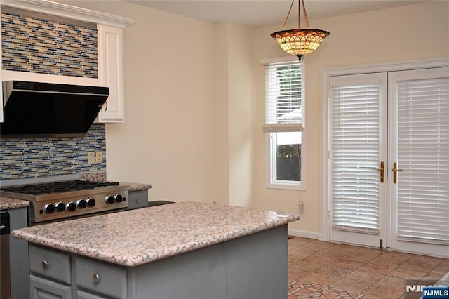 kitchen featuring decorative light fixtures, ventilation hood, gray cabinets, decorative backsplash, and stove