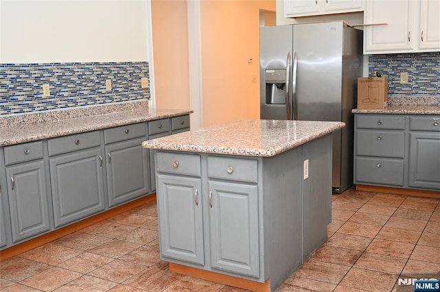 kitchen featuring stainless steel fridge with ice dispenser, decorative backsplash, gray cabinets, and a center island