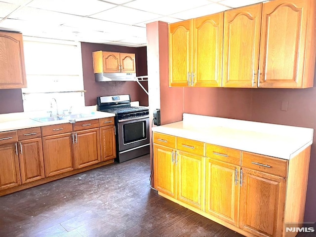 kitchen featuring gas range, sink, a drop ceiling, and dark wood-type flooring