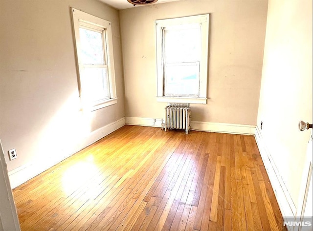 unfurnished room with radiator and light wood-type flooring