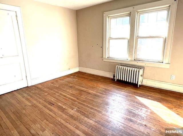 spare room with radiator and dark wood-type flooring