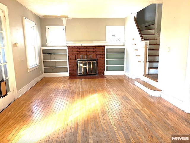 unfurnished living room featuring a brick fireplace and light hardwood / wood-style floors