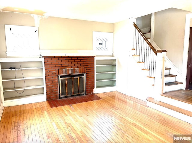 unfurnished living room with a brick fireplace and hardwood / wood-style floors