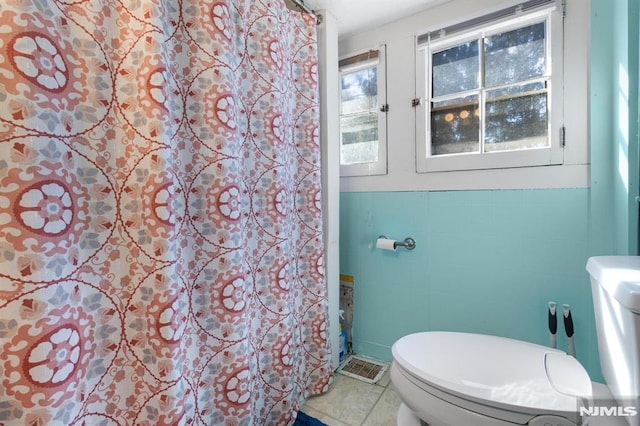 bathroom with tile walls, tile patterned flooring, and toilet