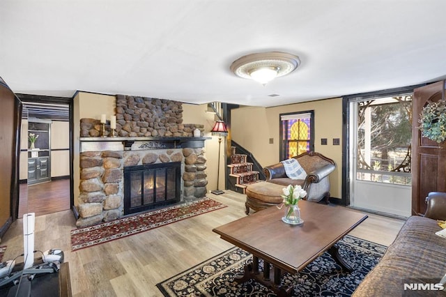 living room featuring hardwood / wood-style flooring and a stone fireplace