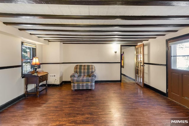 unfurnished room featuring a healthy amount of sunlight, dark hardwood / wood-style floors, and beam ceiling