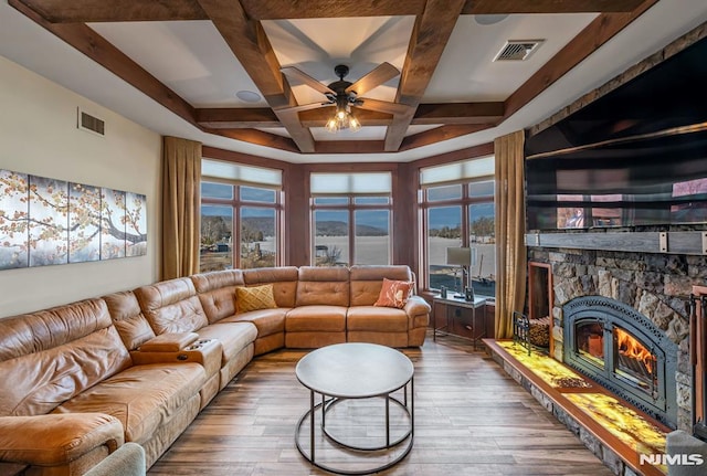 living room featuring ceiling fan, hardwood / wood-style floors, coffered ceiling, and a stone fireplace