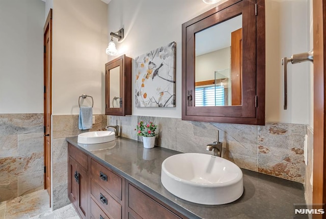 bathroom featuring vanity and tile walls