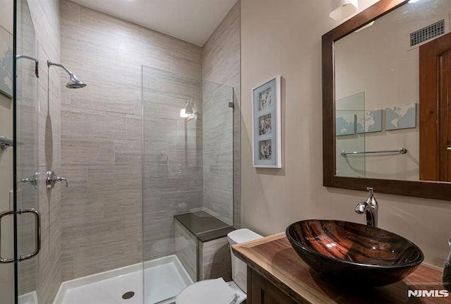 bathroom with toilet, a shower with shower door, and vanity