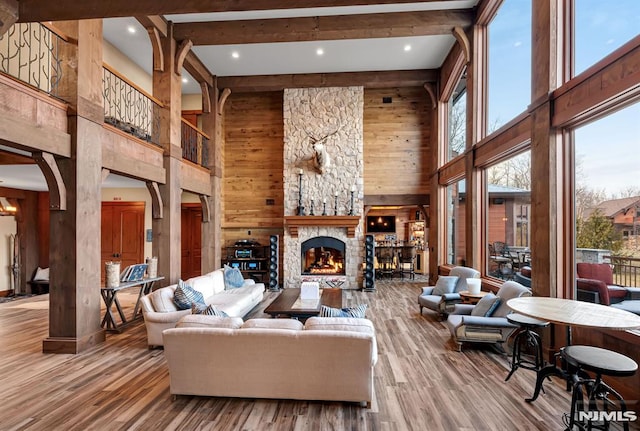 living room with a fireplace, wood-type flooring, a towering ceiling, and plenty of natural light