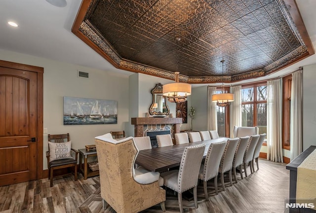 dining room with ornamental molding, a fireplace, a raised ceiling, and parquet flooring