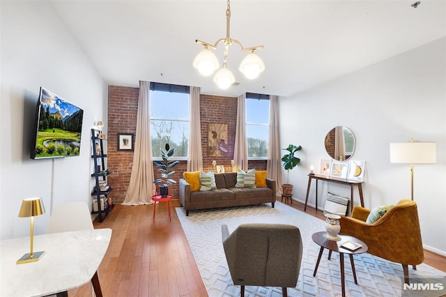 living room featuring light hardwood / wood-style floors, brick wall, and a notable chandelier