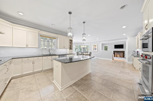 kitchen featuring pendant lighting, ornamental molding, stainless steel appliances, and sink