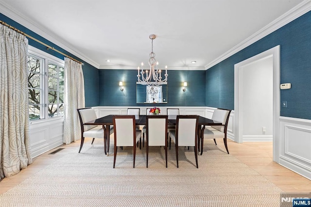 dining room with ornamental molding, an inviting chandelier, and light hardwood / wood-style flooring