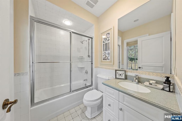 full bathroom with tile walls, tile patterned flooring, vanity, enclosed tub / shower combo, and toilet