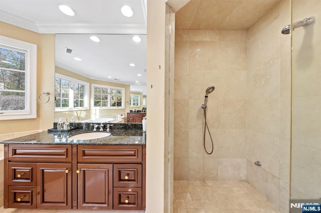 bathroom with crown molding, tiled shower, and vanity