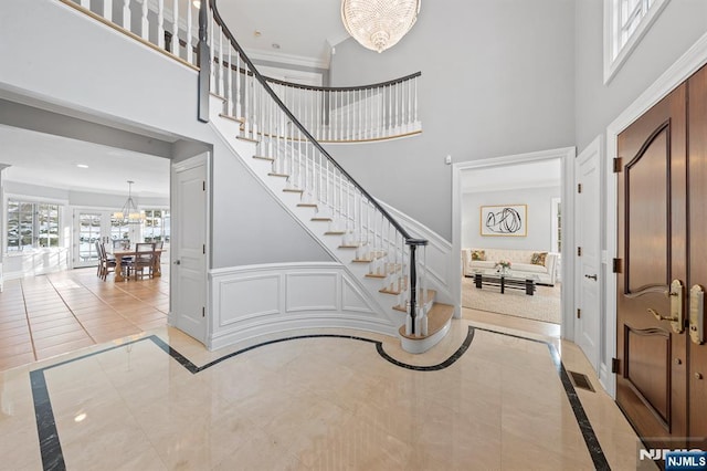 foyer with crown molding and a notable chandelier