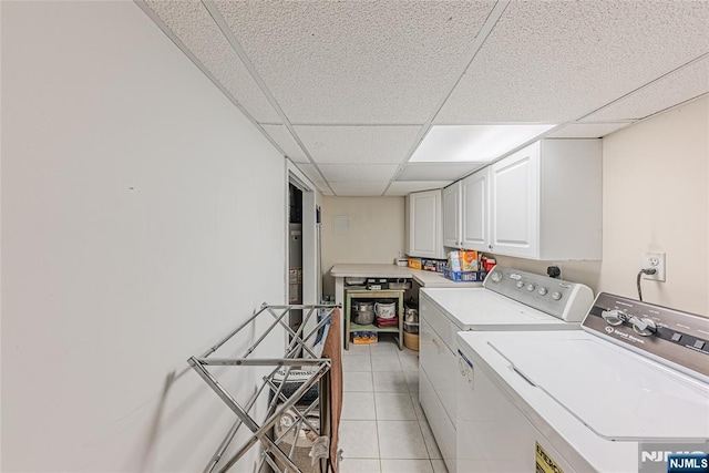 laundry room featuring cabinets, washing machine and dryer, and light tile patterned floors