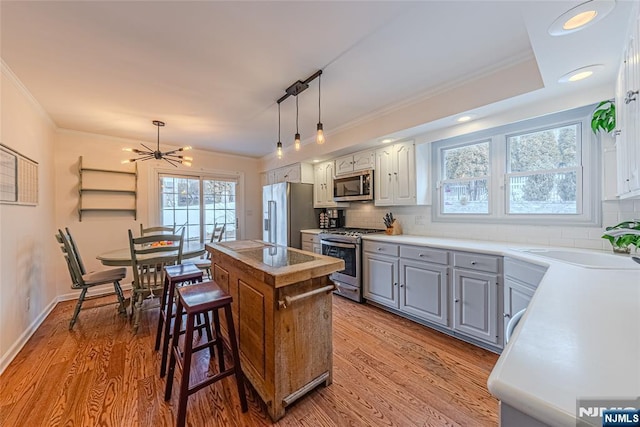 kitchen featuring appliances with stainless steel finishes, light hardwood / wood-style floors, a kitchen island, and gray cabinetry