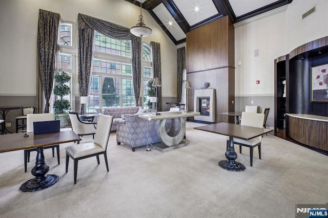 interior space featuring beamed ceiling, a towering ceiling, light carpet, and a large fireplace