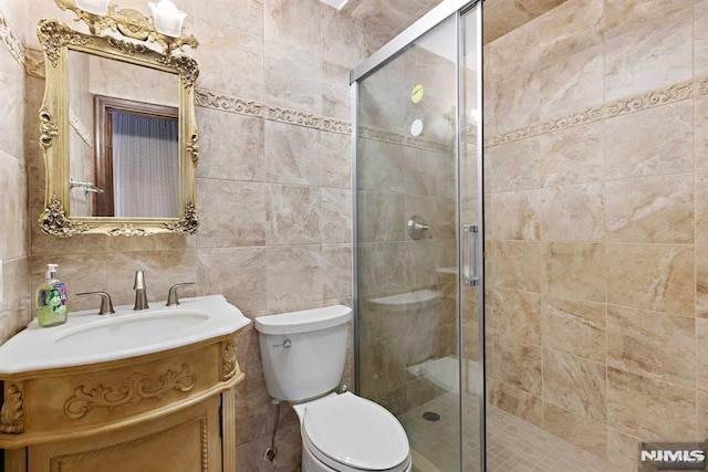 bathroom with walk in shower, toilet, vanity, and tile walls