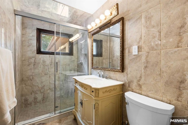 bathroom with tile walls, an enclosed shower, vanity, and toilet