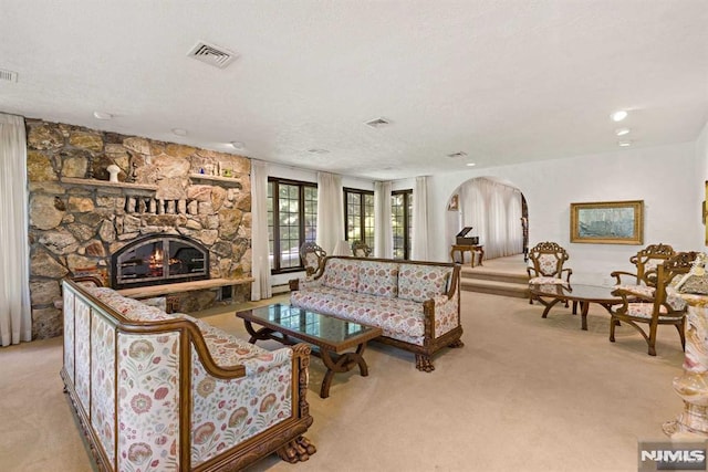 carpeted living room with a textured ceiling and a stone fireplace