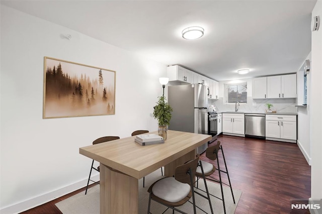 kitchen featuring appliances with stainless steel finishes, backsplash, dark hardwood / wood-style flooring, white cabinets, and sink